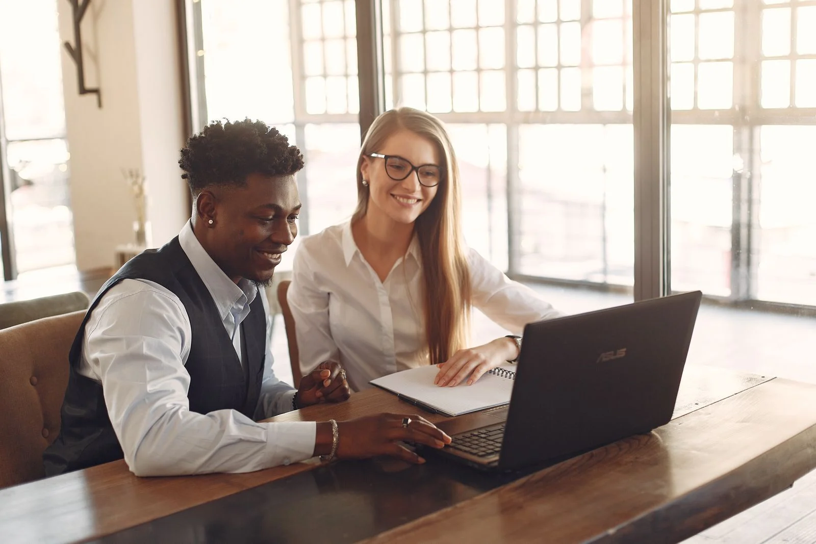 Colegas de trabalho conversando com naturalidade enquanto usam um notebook